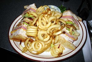 En solid porsjon med Club Sandwich og pommes frites.